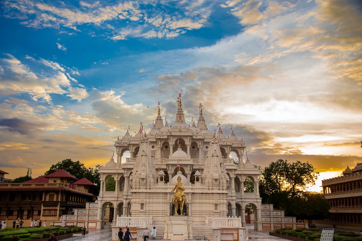 The mandir and golden statue under a sunset sky